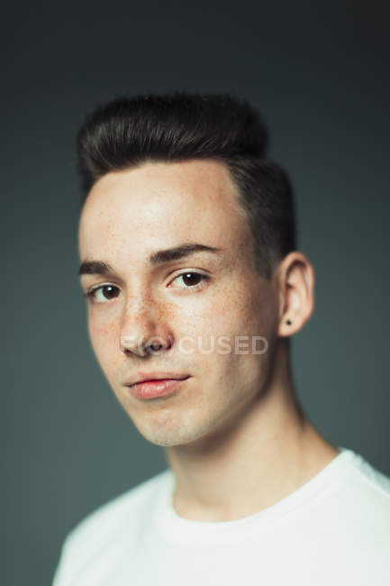 Portrait confident teenage boy with freckles and earring — Stock Photo