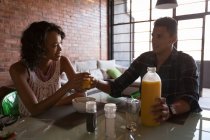 Couple having orange juice in living room at home — Stock Photo