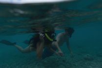 Couple swimming underwater in turquoise sea over rocky bottom — Stock Photo