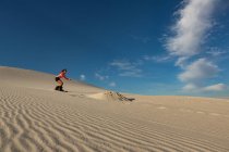 Woman sandboarding on sand dune at desert — Stock Photo