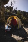 Hiker wrapped in blanket sitting in tent on a sunny day — Stock Photo