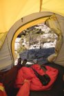 Hiker lying in a tent with camping equipment on a sunny day — Stock Photo