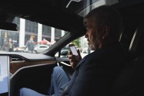 Side view of businessman talking on mobile phone in car — Stock Photo