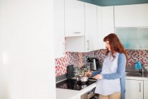 Pregnant woman cooking food in kitchen at home — Stock Photo