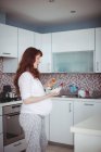 Pregnant woman having salad in kitchen at home — Stock Photo