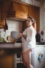 Woman standing and holding a bowl in kitchen at home — Stock Photo