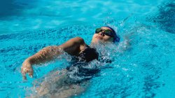 High angle view of young female swimmer swimming backstroke in swimming pool — Stock Photo