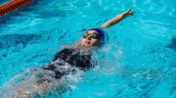 High angle view of young female swimmer swimming backstroke in swimming pool — Stock Photo