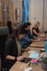 Side view of well dressed businesswoman using graphic tablet while looking at color swatch with colleagues working hard in office — Stock Photo