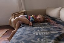 Side view of a Caucasian baby lying on a sofa and smiling, barefoot — Stock Photo