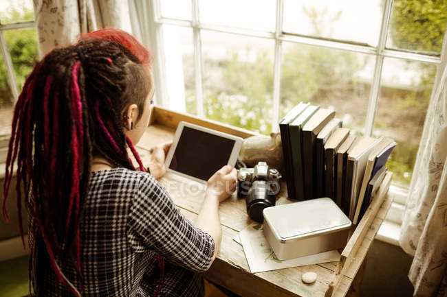 High angle view of young woman using tablet computer by window at home — Stock Photo