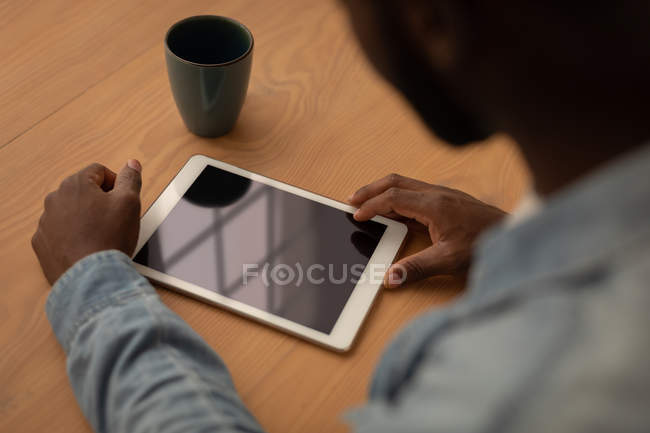 High angle view of African-American man using digital tablet while sitting on chair at home — Stock Photo