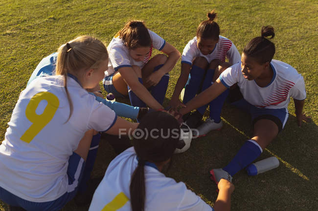 High angle view of happy diverse female soccer players forming a hand stack on the field on a sunny day — Stock Photo