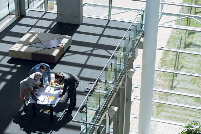 High angle view of male and female architects discussing over blueprint in office. — Stock Photo