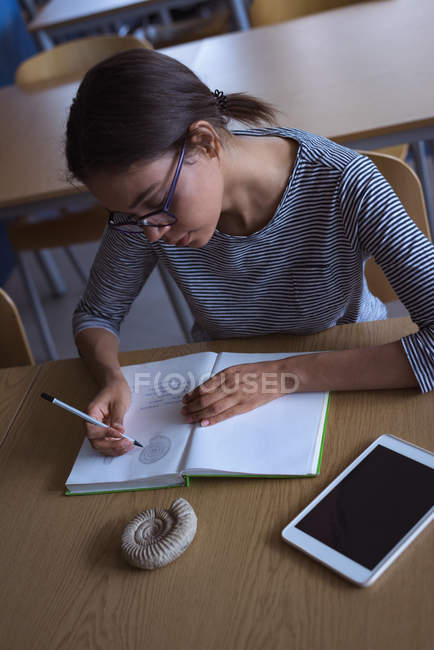 High angle view of female university student practicing diagram while studying at desk in classroom — Stock Photo