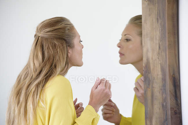 Elegant woman examining make-up in mirror — Stock Photo