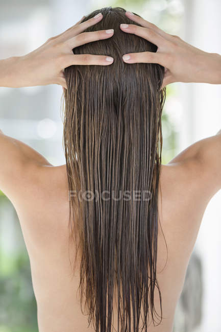 Rear view of woman massaging wet long hair — Stock Photo