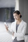 Chinese businesswoman using smartphone on street — Stock Photo