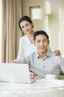 Young Chinese couple using laptop at home — Stock Photo