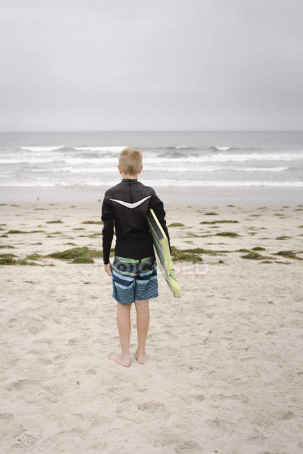 Ragazzo in piedi sulla spiaggia di sabbia — Foto stock