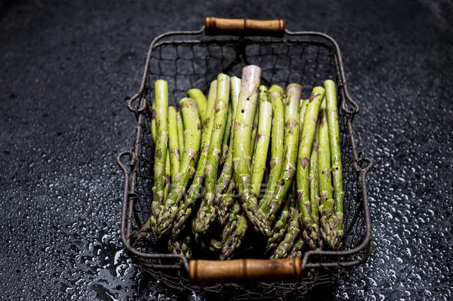 High angle view of freshly picked green asparagus in metal basket. — Stock Photo