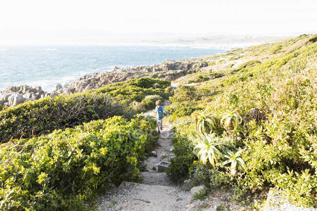 Un ragazzo che corre lungo il sentiero verso la spiaggia a De Kelders. — Foto stock