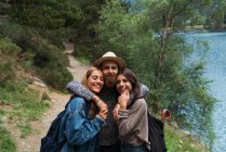 Tres amigos abrazos sobre el lago de montaña - foto de stock