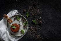 Chocolate cake with mint, chocolate pieces and cinnamon on black background — Stock Photo