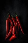 Fresh red spicy chilli peppers on black background — Stock Photo