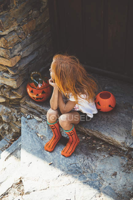 Ragazza seduta con cesto di zucca sul portico — Foto stock