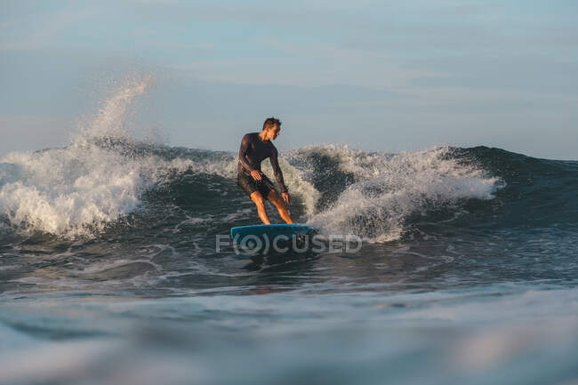 Surf maschile tra acqua di mare ondulata con spruzzi a Bali, Indonesia — Foto stock