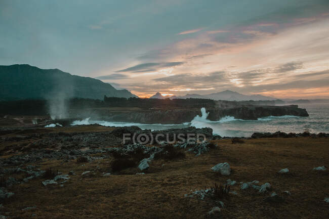 Picturesque view of high shore near stormy sea and beautiful cloudy sky at sunset in Bufones de Pria, Asturias, Spain — Foto stock