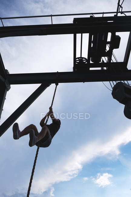 From below unrecognizable guy climbing rope while working out in outdoor gym — Stock Photo