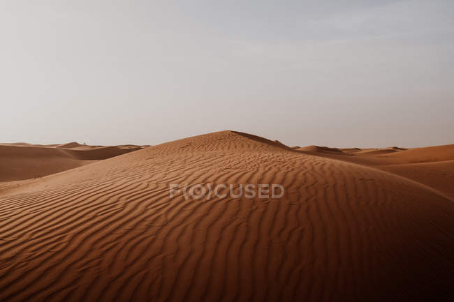 Collina dalla sabbia asciutta in mezzo al grande deserto contro il cielo grigio in Marocco — Foto stock