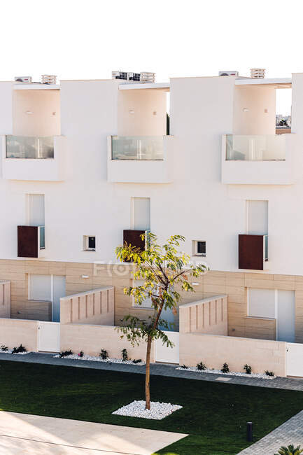 Esterni casa contemporanea contro piscina con acqua increspata e prato sotto il cielo blu in città — Foto stock