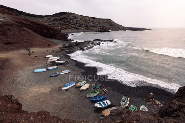 Drone vista di barche sulla spiaggia Ciclos contro l'oceano schiumoso e vulcano Guincho a Golfo Yaiza Lanzarote Isole Canarie Spagna — Foto stock