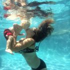 Mother kissing baby underwater — Stock Photo