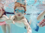 Boy swimming underwater with friends — Stock Photo