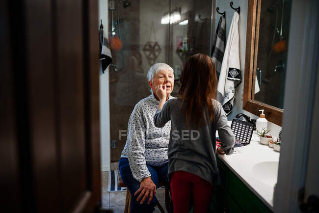 Girl putting make-up on her Grandmother — Stock Photo