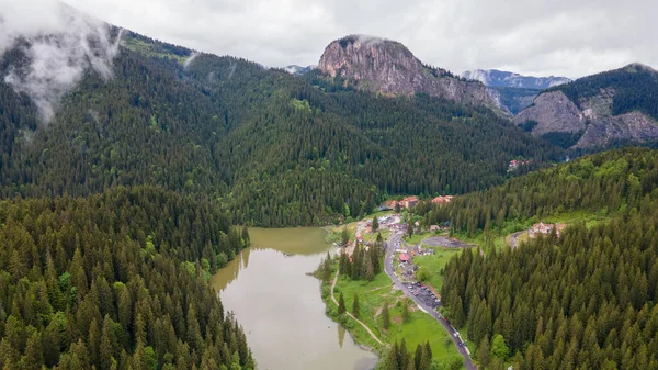 Aerial photography of Red lake in Romania, Neamt county. Panorama photography taken from a drone with view of the lake, clouds and mountains in the background. Birds eye view over mountain lake