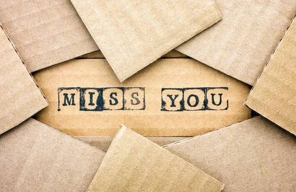 Words Miss You make by black alphabet stamps on cardboard