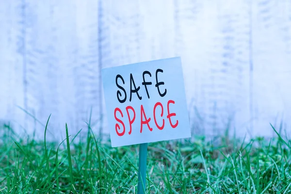 Text sign showing Safe Space. Conceptual photo a place or room in which you are protected from harm or danger Plain empty paper attached to a stick and placed in the green grassy land.