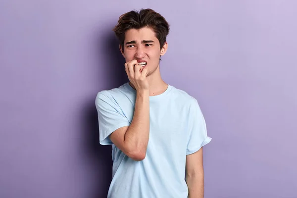 puzzled nervous man biting his nails , expressing negative feeling