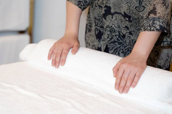 The girl prepares a workplace massage bed in the spa for the reception of clients. The maid is preparing a room for the spa salon. Woman masseuse in the workplace. The concept of health and beauty.