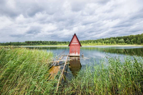 A small red wooden house near the lake and the forest, Latvia