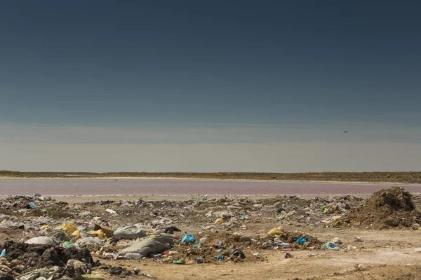 Illegal garbage dump near the water technical lake with pink water