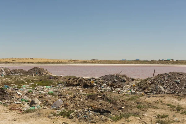 Illegal garbage dump near the water technical lake with pink water