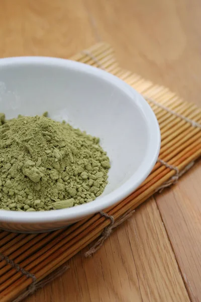 Green Matcha tea powder in a bowl on wooden background. Powdered matcha green tea on wooden table