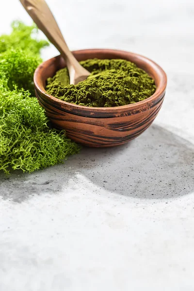 Green powder chlorella, spirulina on gray concrete background. Concept dieting, detox, healthy superfood, which contains protein. Copy space.