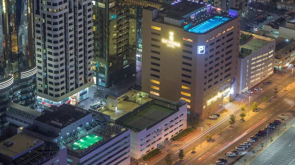 Car parking lot with rooftop swimming pool viewed from above night timelapse, Aerial top view. Dubai, UAE